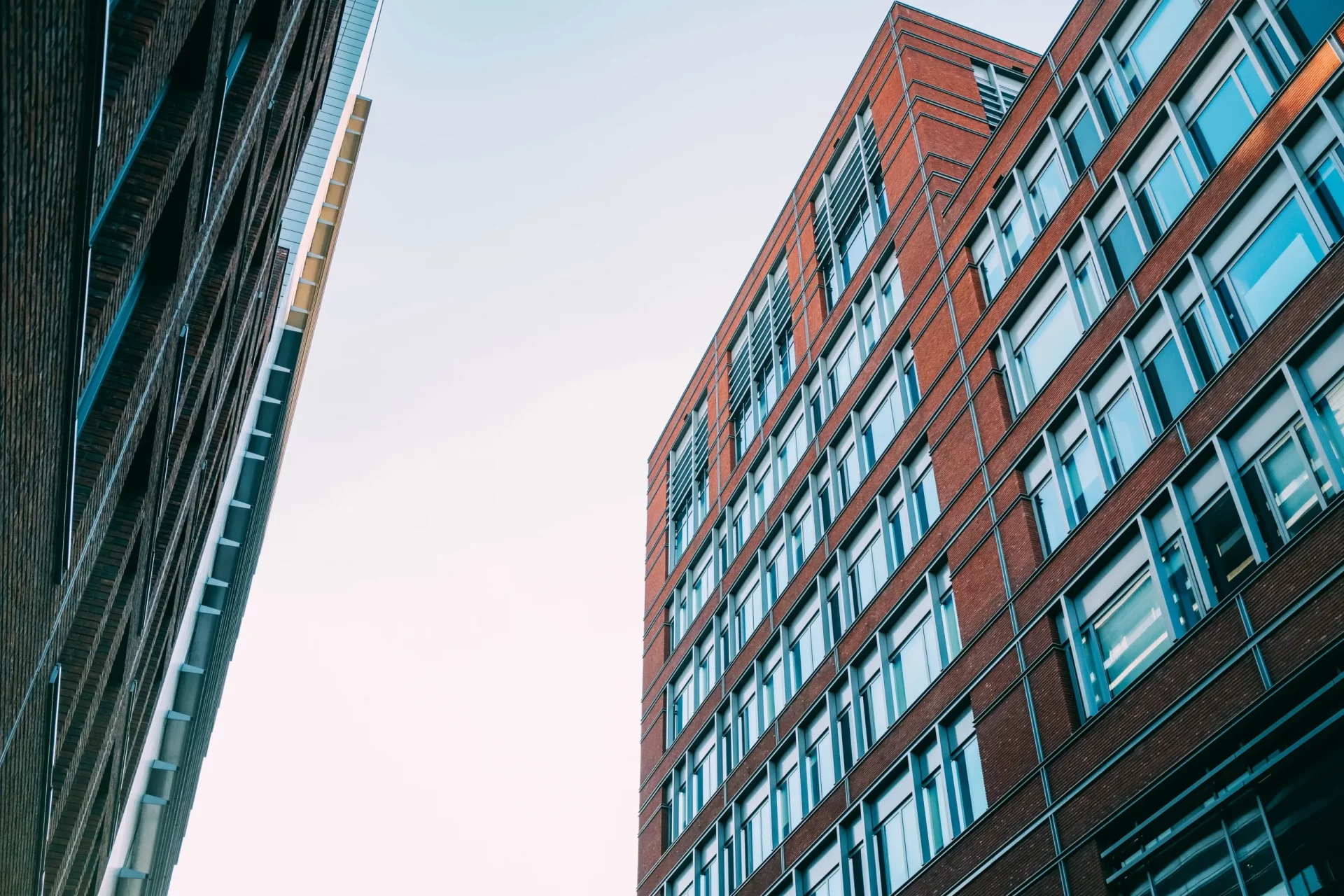 low-angle-shot-concrete-apartment-buildings-with-lot-windows-scaled